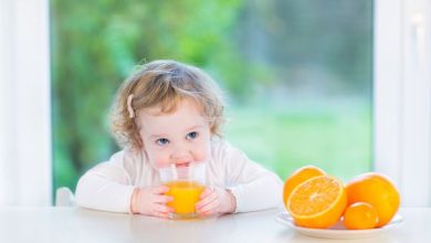 59172357 دختر ناز کودک نو پا نوشیدن آب پرتقال در میز سفید نشسته