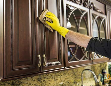 man cleaning wooden kitchen cabinet